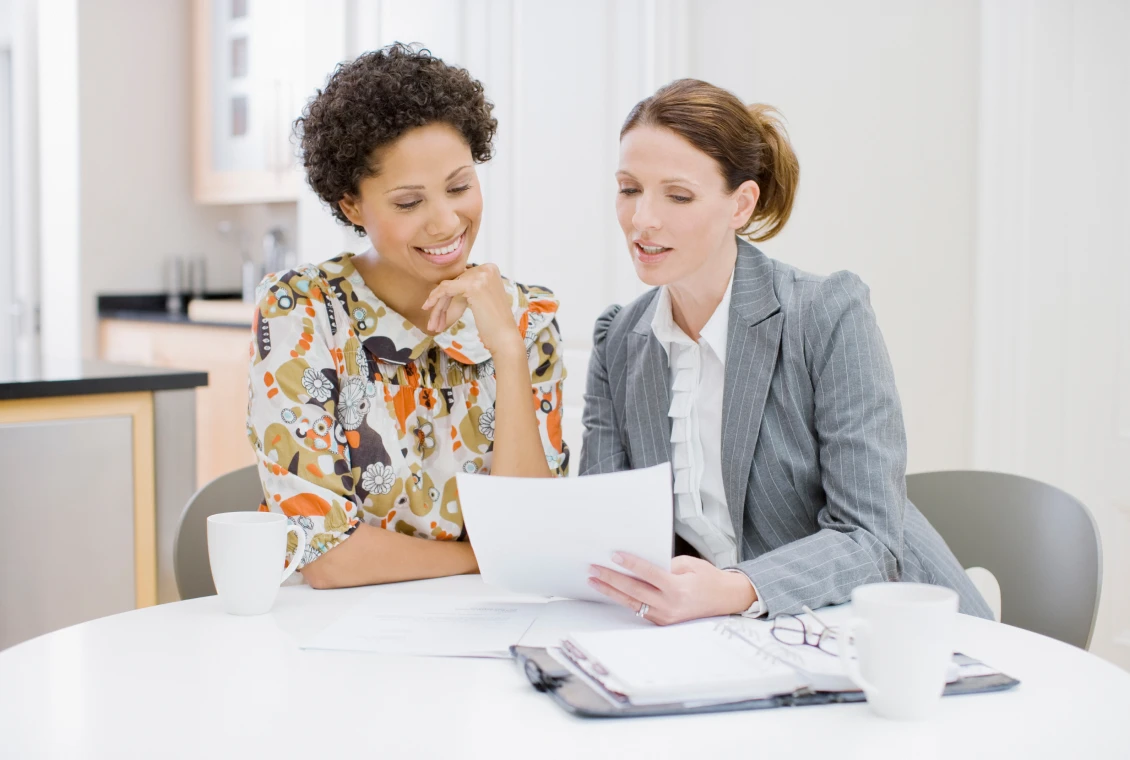 Colleagues discussing paperwork in office setting